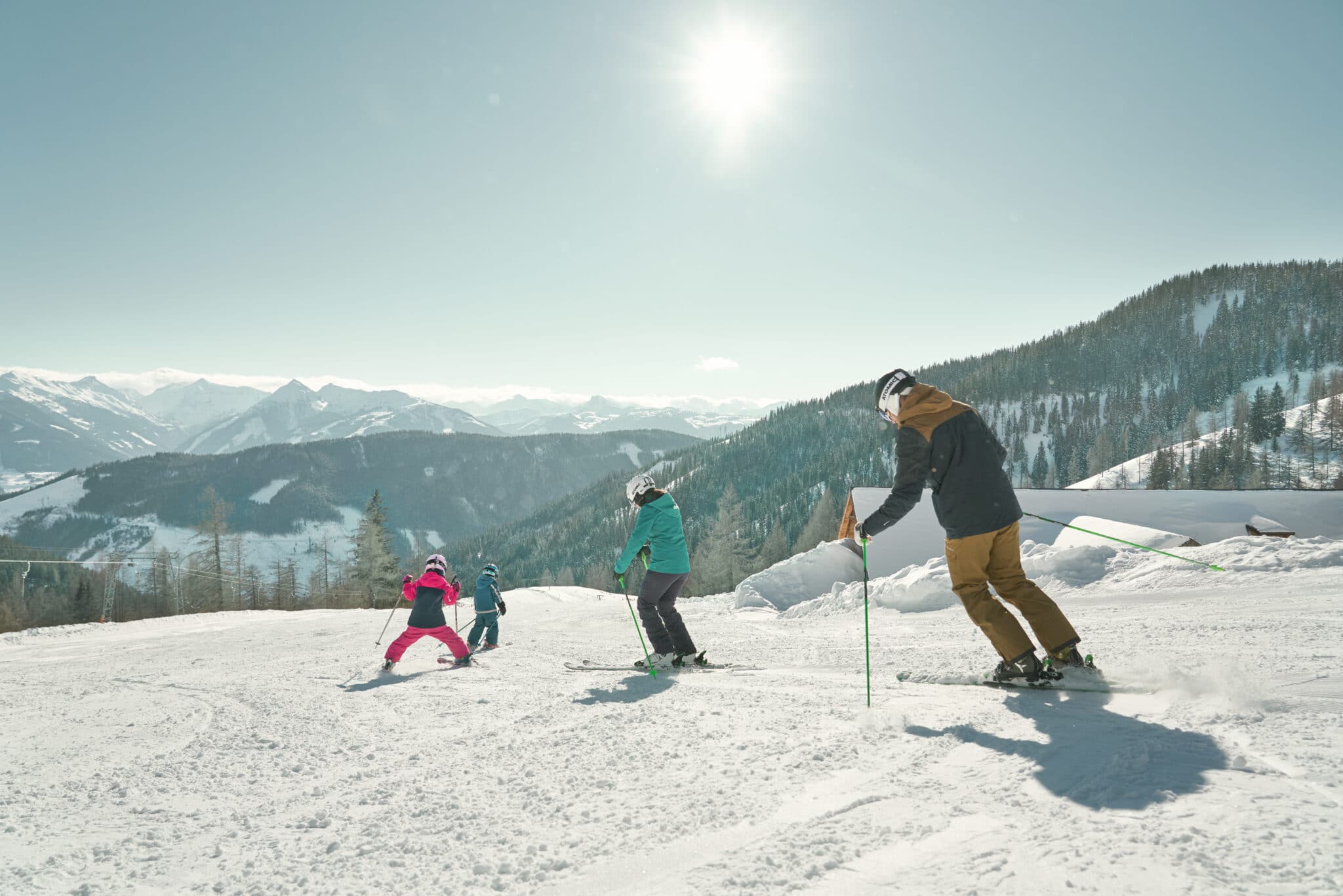 Familie mit Kindern beim Skifahren auf einer Skipiste in den Bergen bei gutem Wetter